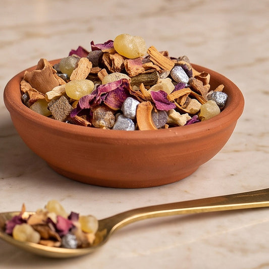 Engel der Kraft, Engelräucherung von Berk, 40 ml im Kugelglas: Nahaufnahme der Terracottaschale mit gelben Harztränen, hellen Wurzelstücken, Rosenblättern und Orangenschale und dem Messinglöffel auf der Marmortheke – Spirit of Gaia