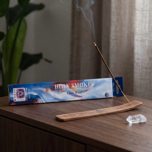 Clear Wind Räucherstäbchen Holy Smokes Blue Line: glimmendes Räucherstäbchen mit feinem Rauch im Holzhalter, dahinter die Packung, auf einem Sideboard am Abend