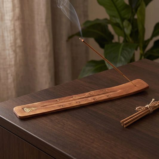 Räucherstäbchenhalter Holz Buddha in Benutzung mit feinem Rauch auf einem dunklen Holz-Sideboard am Abend