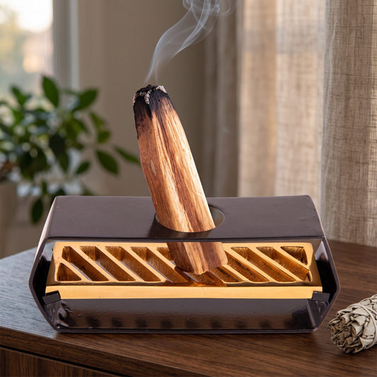 Halter für Palo Santo Sticks in Benutzung mit feinem Rauch auf einem dunklen Holz-Sideboard am Abend