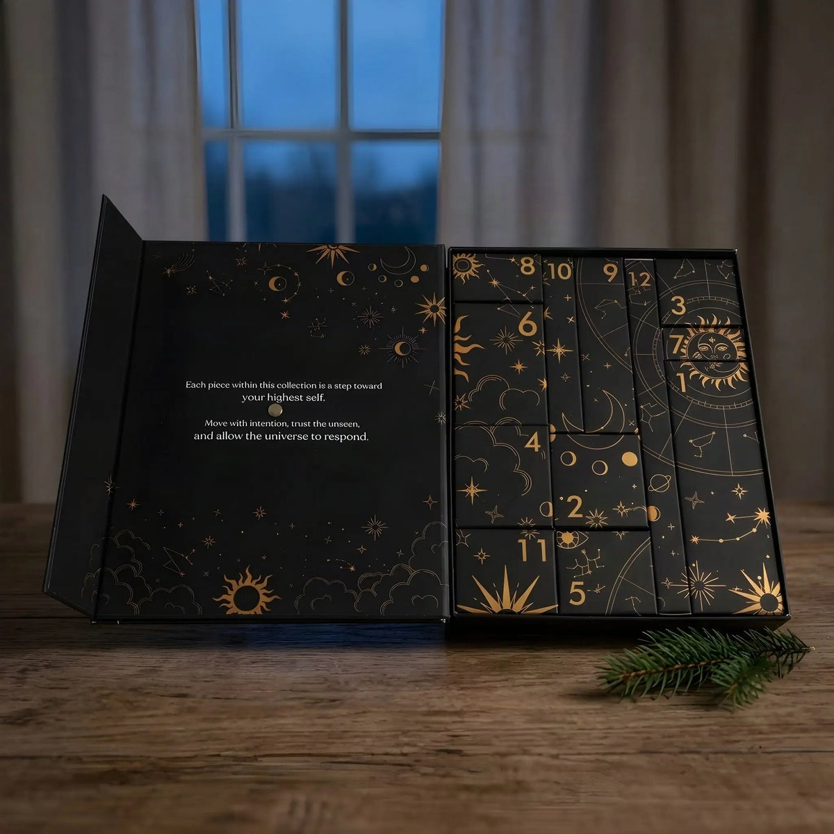 Geöffnete Kalender-Box mit zwölf nummerierten Schachteln am Abend auf einem Holztisch, daneben ein Tannenzweig