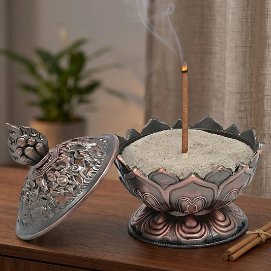 Räucherstäbchenhalter Lotus kupferfarbig in Benutzung mit feinem Rauch auf einem dunklen Holz-Sideboard am Abend