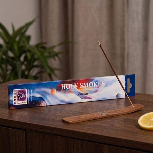 Zitrone Räucherstäbchen Holy Smokes Blue Line: glimmendes Räucherstäbchen mit feinem Rauch im Holzhalter, dahinter die Packung, auf einem Sideboard am Abend