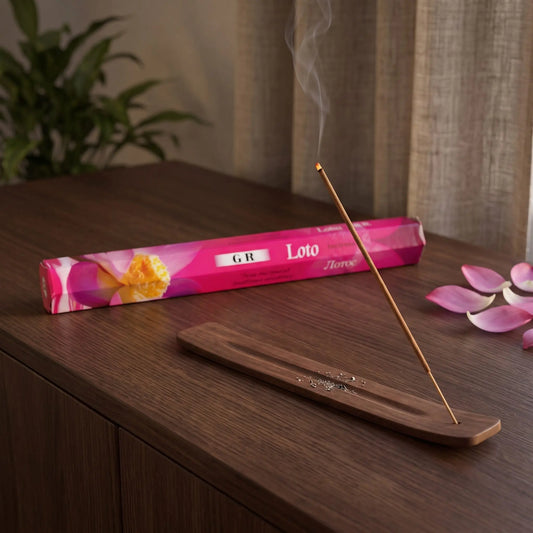 GR Lotus Räucherstäbchen: glimmendes Räucherstäbchen mit feinem Rauch im Holzhalter, dahinter die Sechseck-Packung, auf einem Sideboard am Abend