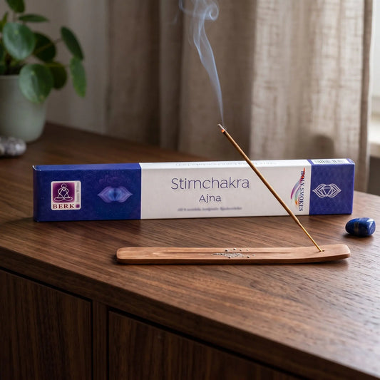Stirnchakra Räucherstäbchen Holy Smokes: glimmendes Räucherstäbchen mit feinem Rauch im Holzhalter, dahinter die Packung, auf einem Sideboard am Abend