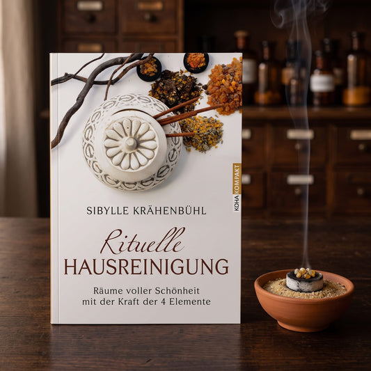 Buch Rituelle Hausreinigung liegt auf einem dunklen Holztisch, daneben eine Schale mit glühender Kohle, Harz und einem Rauchfaden