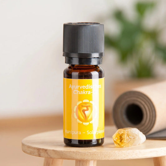 Ayurvedisches Chakra-Öl Manipura (Solarplexus-Chakra): 10-ml-Fläschchen auf einem Holzhocker neben einer gerollten Yogamatte, daneben Citrin