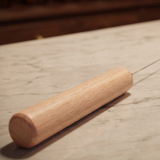 Tensor aus Buchenholz mit Federstahlrute, ca. 41,5 cm: Nahaufnahme des Buchenholzgriffs mit der Federstahlrute auf der Marmortheke – Spirit of Gaia