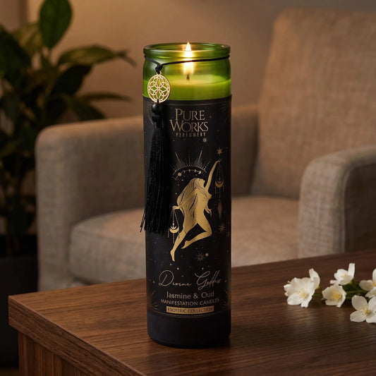 Manifestationskerze Divine Goddess (Jasmin & Oud): brennende Glaskerze auf einem dunklen Holztisch im Wohnzimmer am Abend, daneben weiße Jasminblüten