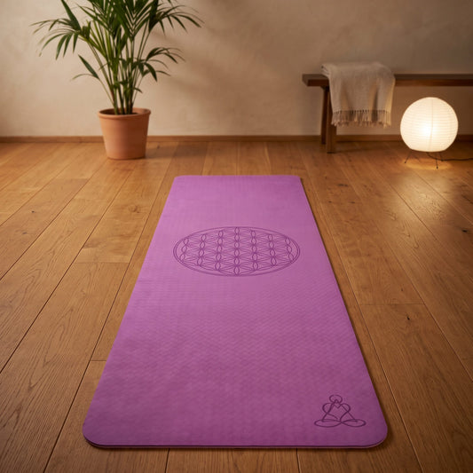 EcoBalance Yogamatte aus TPE, 182 × 61 cm, 6 mm, Blume des Lebens, lila/zartlila: ausgerollt auf dem Holzboden, in der Mitte die eingelaserte Blume des Lebens, warmes Abendlicht – Spirit of Gaia