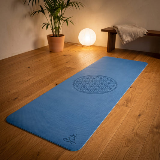 EcoBalance Yogamatte aus TPE, 182 × 61 cm, 6 mm, Blume des Lebens, dunkel-/hellblau: ausgerollt auf dem Holzboden, in der Mitte die eingelaserte Blume des Lebens, warmes Abendlicht – Spirit of Gaia