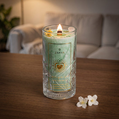 Die Kerze Heilung der Seele brennt auf einem dunklen Holztisch im Wohnzimmer am Abend, daneben zwei Jasminblüten