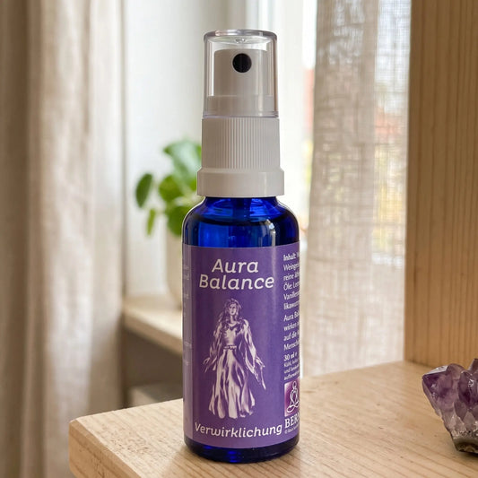 Energiespray Verwirklichung (Aura Balance): Sprühflasche auf einem hellen Holzregal am Fenster mit Leinenvorhang, daneben ein Amethyst