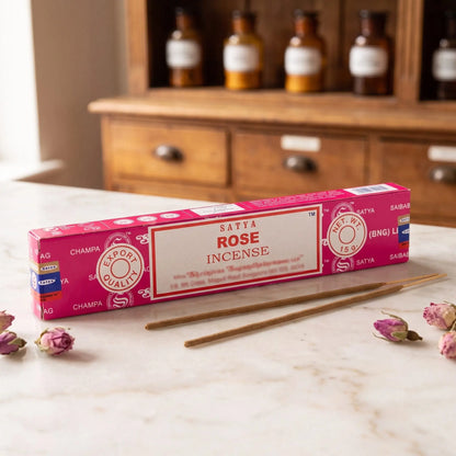 Satya Rose Räucherstäbchen: 15-g-Packung auf einer Marmortheke vor einem Apothekerschrank, daneben zwei lose Räucherstäbchen – Spirit of Gaia
