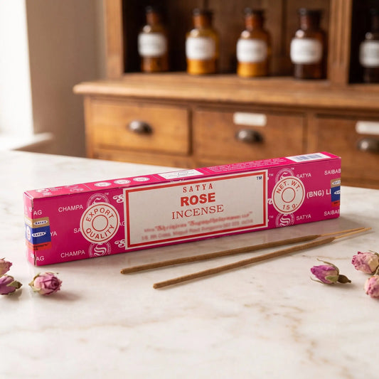 Satya Rose Räucherstäbchen: 15-g-Packung auf einer Marmortheke vor einem Apothekerschrank, daneben zwei lose Räucherstäbchen – Spirit of Gaia