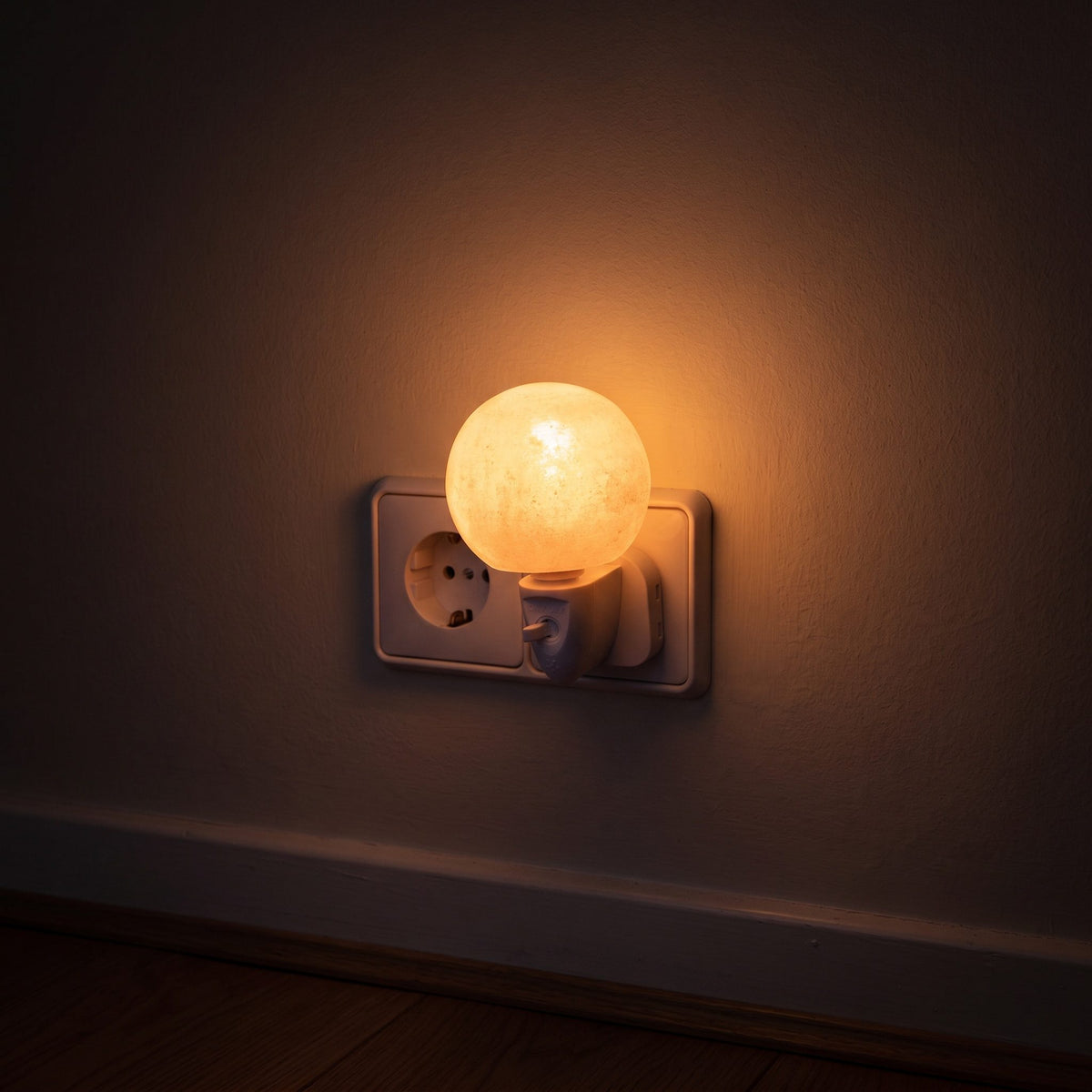 Das Salzkristall-Nachtlicht Kugel in der Steckdose eines dunklen Flurs, das Licht bildet einen weichen Kreis auf der Wand