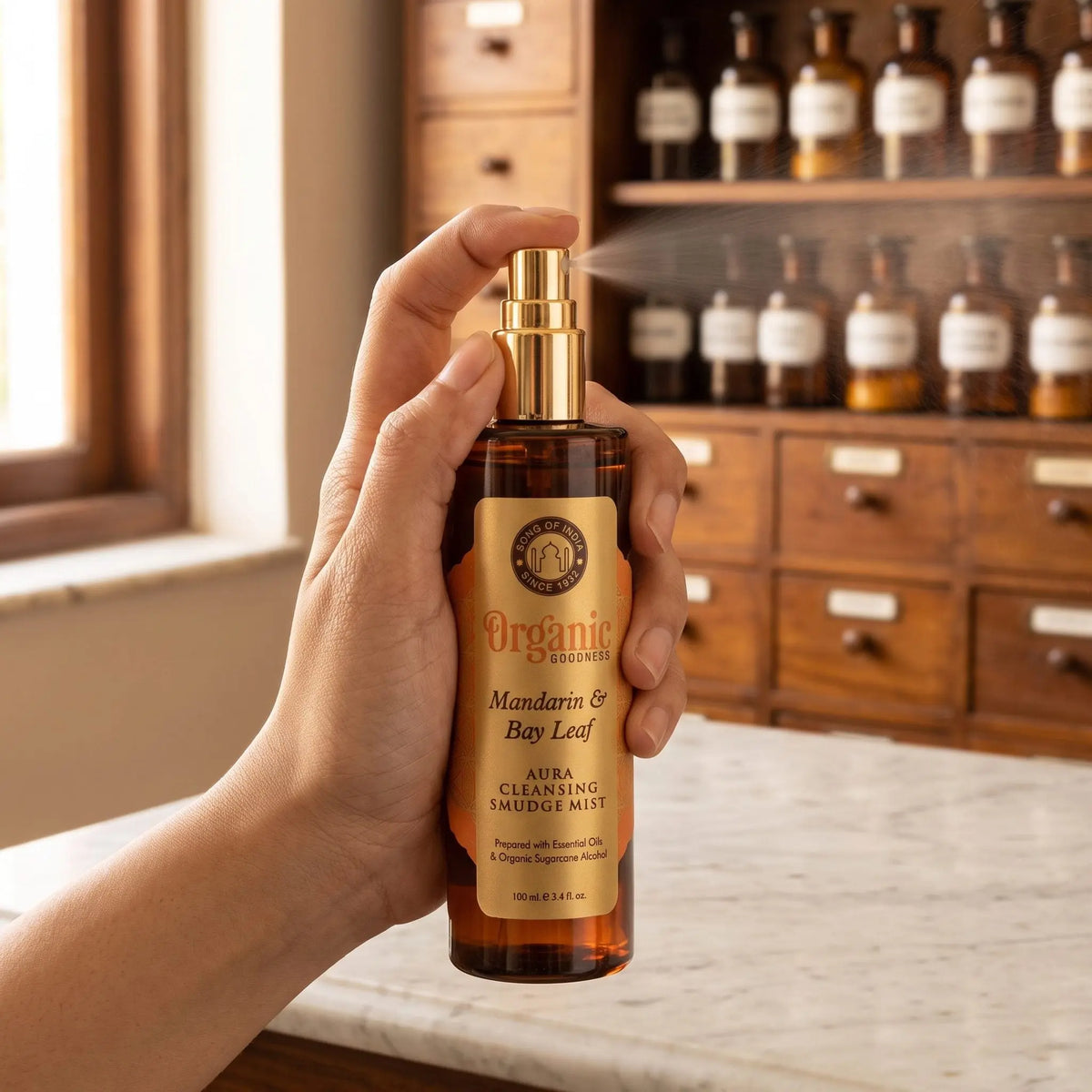 Hand sprüht einen feinen Nebel aus dem Aura Reinigungsspray Mandarine und Lorbeerblatt in den Raum