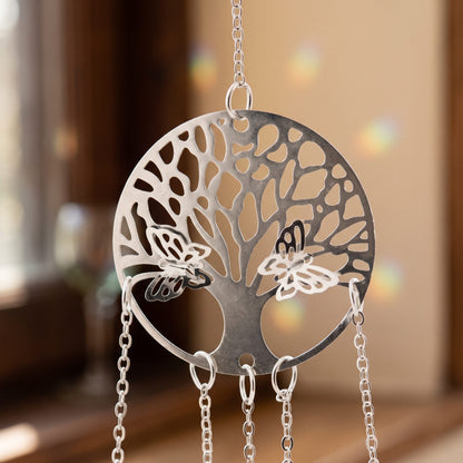 Nahaufnahme der Edelstahlscheibe des Yggdrasil Suncatchers mit ausgeschnittenem Baum, zwei kleinen Schmetterlingen und den Kettenansätzen