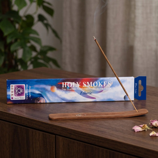 Etheric Räucherstäbchen Blue Line: glimmendes Räucherstäbchen mit feinem Rauch im Holzhalter, dahinter die Packung, auf einem Sideboard am Abend