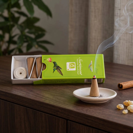 Green Line Räucherkegel Sortiment naturrein, Holy Smokes: glimmender Räucherkegel mit feinem Rauch auf einem Keramiktellerchen, dahinter die geöffnete Packung, auf einem Sideboard am Abend