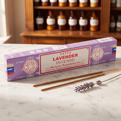 Satya Lavender Räucherstäbchen: 15-g-Packung auf einer Marmortheke vor einem Apothekerschrank, daneben zwei lose Räucherstäbchen – Spirit of Gaia