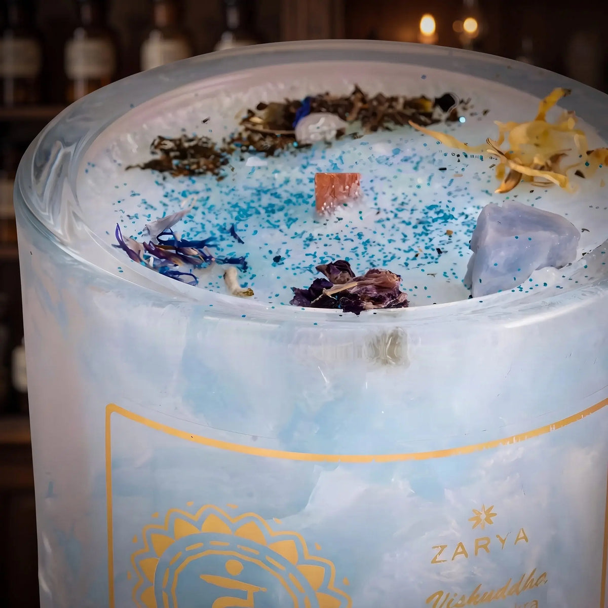 Chakra-Kerze Halschakra Vishuddha mit Aquamarin und Calcit, Duft Minze und Mandel: Nahaufnahme der Wachsoberfläche mit Edelsteinen, getrockneten Blüten und Holzdocht – Spirit of Gaia