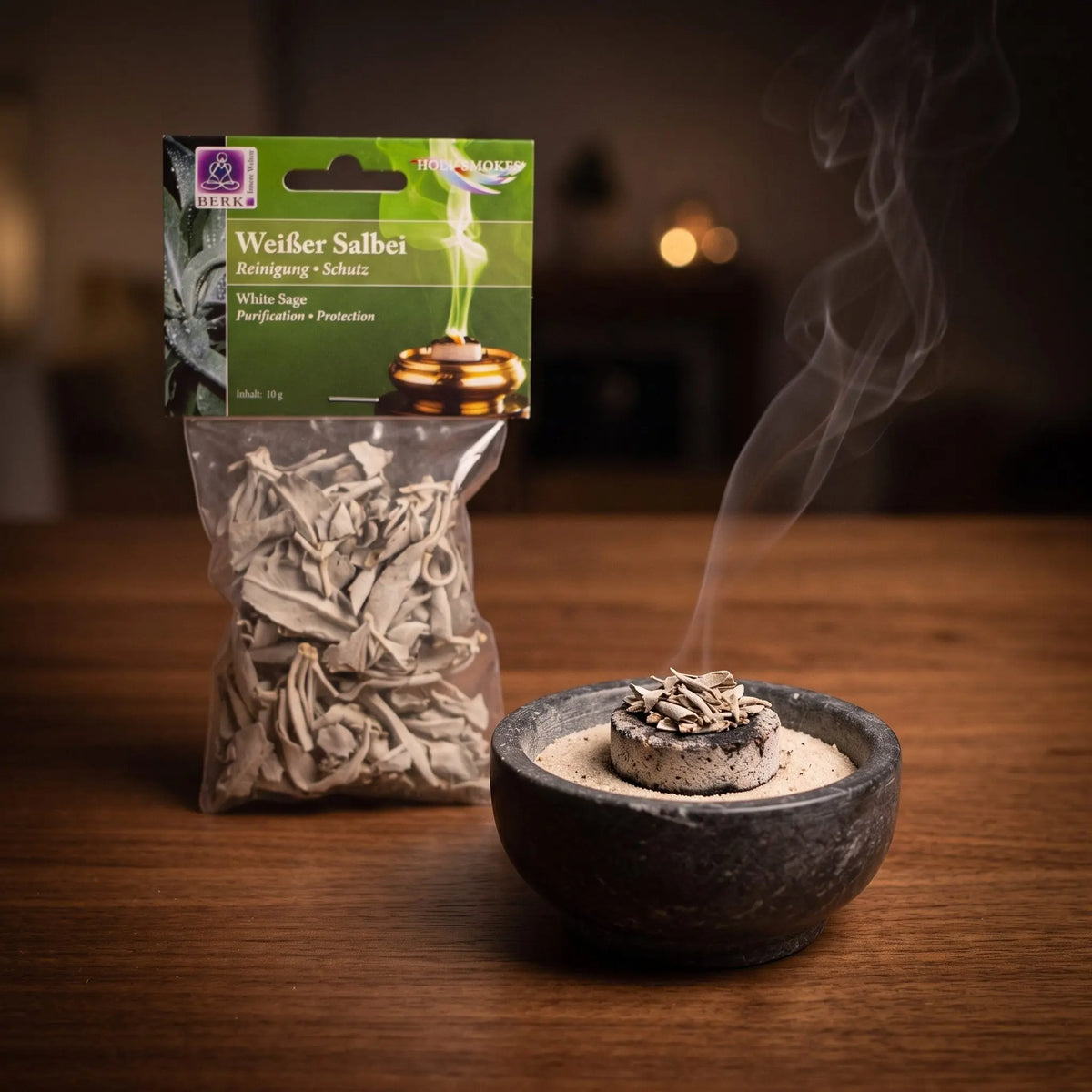 Weißer Salbei, lose in der Tüte, von Berk, 10 g: eine Prise Weißer Salbei glimmt auf der Räucherkohle, dahinter die Tüte, feiner Rauch steigt auf einer dunklen Holzplatte am Abend auf – Spirit of Gaia