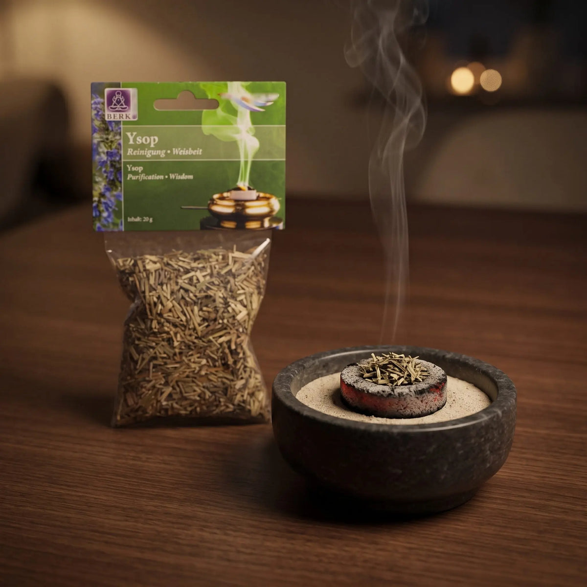 Ysop, sortenreines Räucherwerk von Berk, 20 g: eine Prise Ysop glimmt auf der Räucherkohle, dahinter die Tüte, feiner Rauch steigt auf einer dunklen Holzplatte am Abend auf – Spirit of Gaia