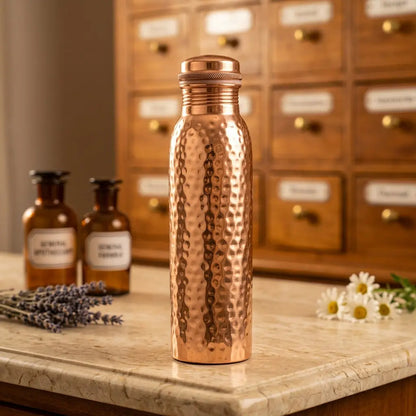 Kupfer-Trinkflasche Ayurveda gehämmert auf Marmortheke vor Apothekerschrank – Spirit of Gaia