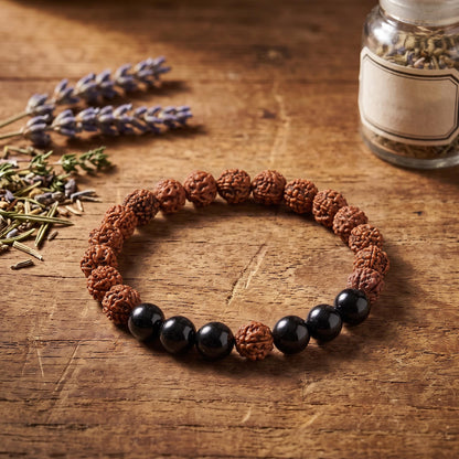 Rudraksha Armband mit schwarzem Turmalin auf einem Holztisch neben Lavendel und einem Glas mit Kräutern