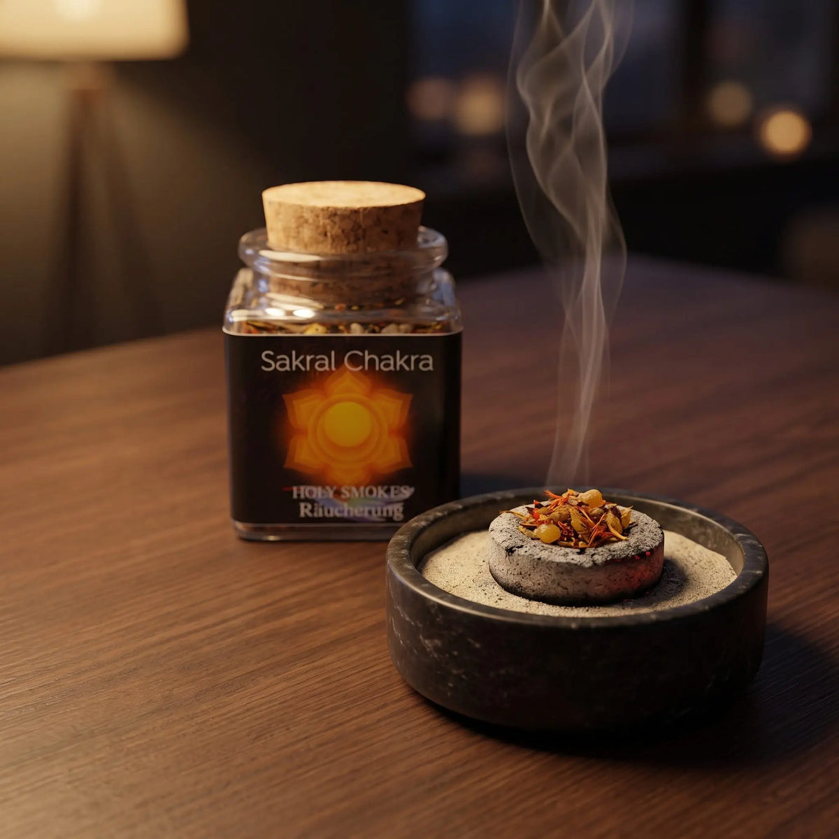 Sakralchakra, Chakra-Räuchermischung von Berk, 50 ml im Korkglas: eine Prise der Mischung glimmt auf der Räucherkohle, dahinter das Korkglas mit schwarzem Etikett, feiner Rauch steigt auf einer dunklen Holzplatte am Abend auf – Spirit of Gaia