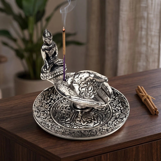 Räucherstäbchenhalter Hände mit Buddha in Benutzung mit feinem Rauch auf einem dunklen Holz-Sideboard am Abend