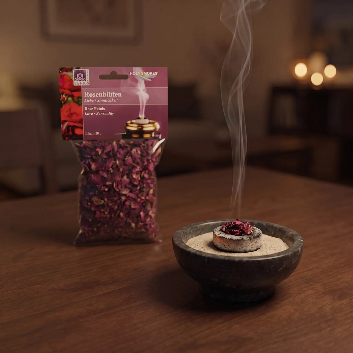 Rosenblüten, sortenreines Räucherwerk von Berk, 20 g: eine Prise Rosenblüten glimmt auf der Räucherkohle, dahinter die Tüte, feiner Rauch steigt auf einer dunklen Holzplatte am Abend auf – Spirit of Gaia