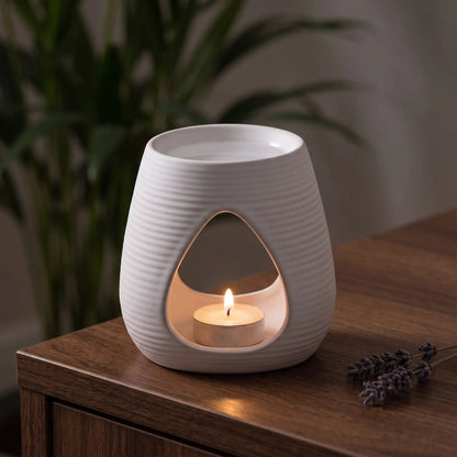Aromalampe Pure White: mit brennendem Teelicht auf einem Holz-Sideboard im Wohnzimmer am Abend, daneben ein Lavendelzweig