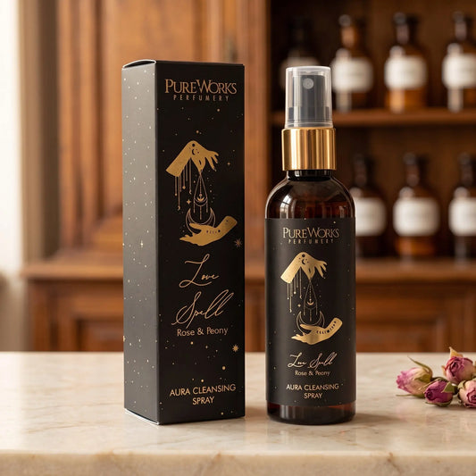 Aura-Spray Love Spell (Rose & Pfingstrose) von Pure Works: Sprühflasche mit Goldkragen und schwarze Schachtel auf Marmortheke vor Apothekerschrank – Spirit of Gaia