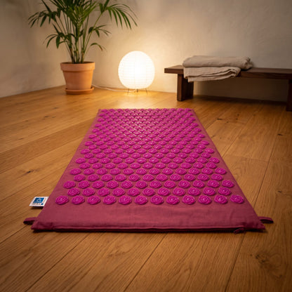 Lotus Akupressurmatte, 78 × 45 cm, Baumwollbezug beerenrot, Lotus-Spitzen: ausgelegt auf dem Holzboden eines ruhigen Meditationsraums am Abend – Spirit of Gaia