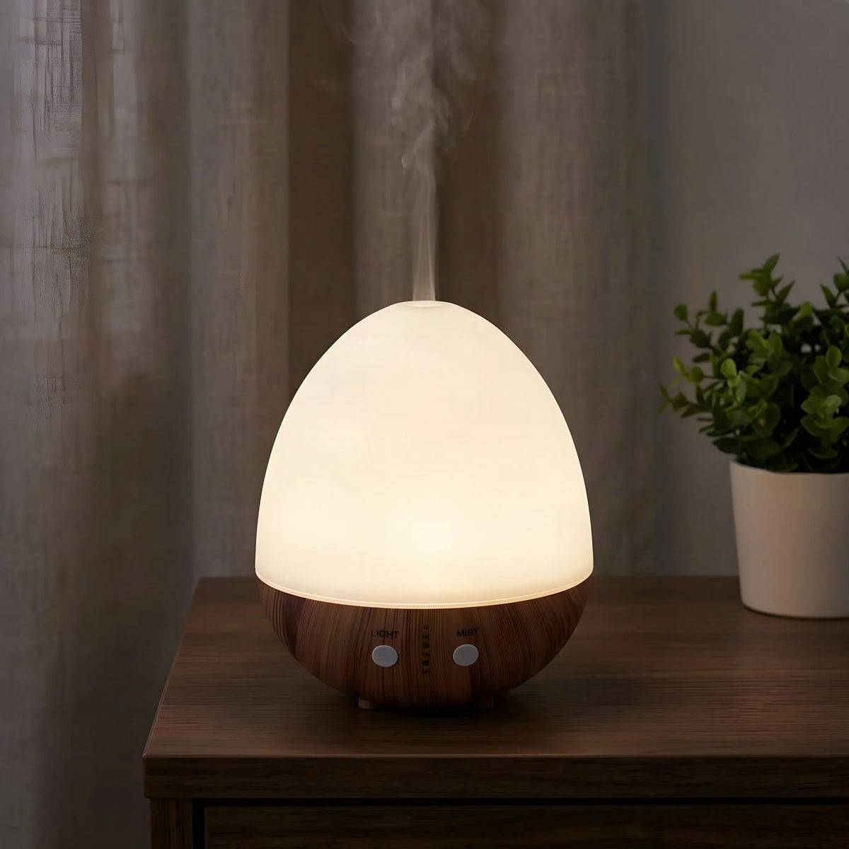 Aroma Diffuser Oval Weiß am Abend: die ganze Haube leuchtet warm, Nebel steigt auf