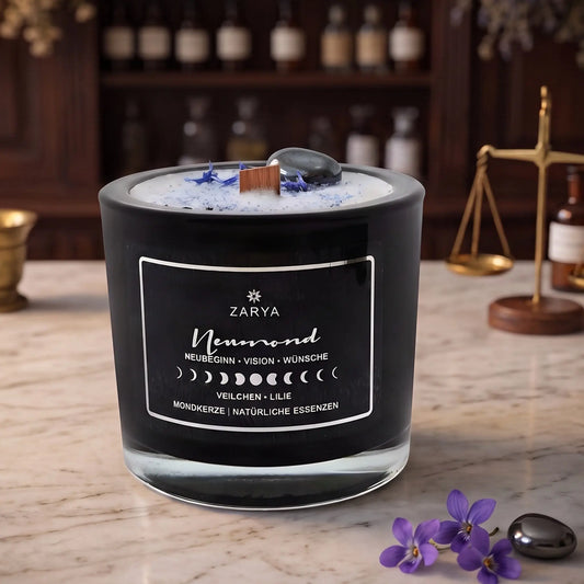 Zeremonie Kerze Neumond mit Hämatit, Duft Veilchen und Lilie: Kerze im Glas auf der Marmortheke einer alten Apotheke am Abend, daneben ein paar Veilchenblüten und ein Hämatit – Spirit of Gaia