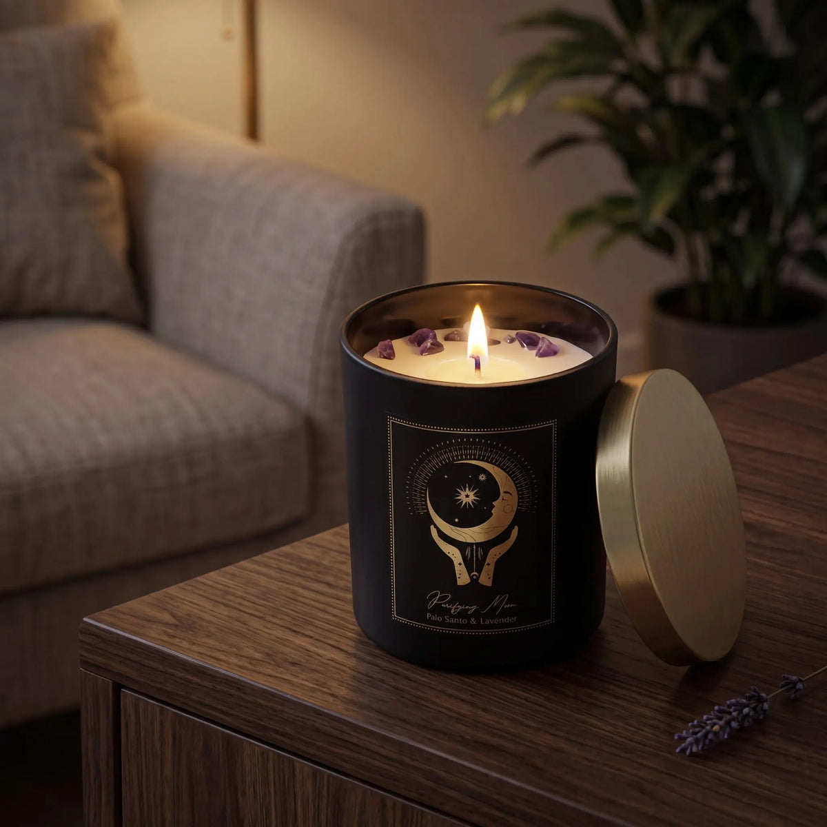 Manifestationskerze Purifying Moon mit Amethyst (Palo Santo & Lavendel): brennende Kerze im schwarzen Glas auf einem dunklen Holztisch im Wohnzimmer am Abend, daneben ein Lavendelzweig