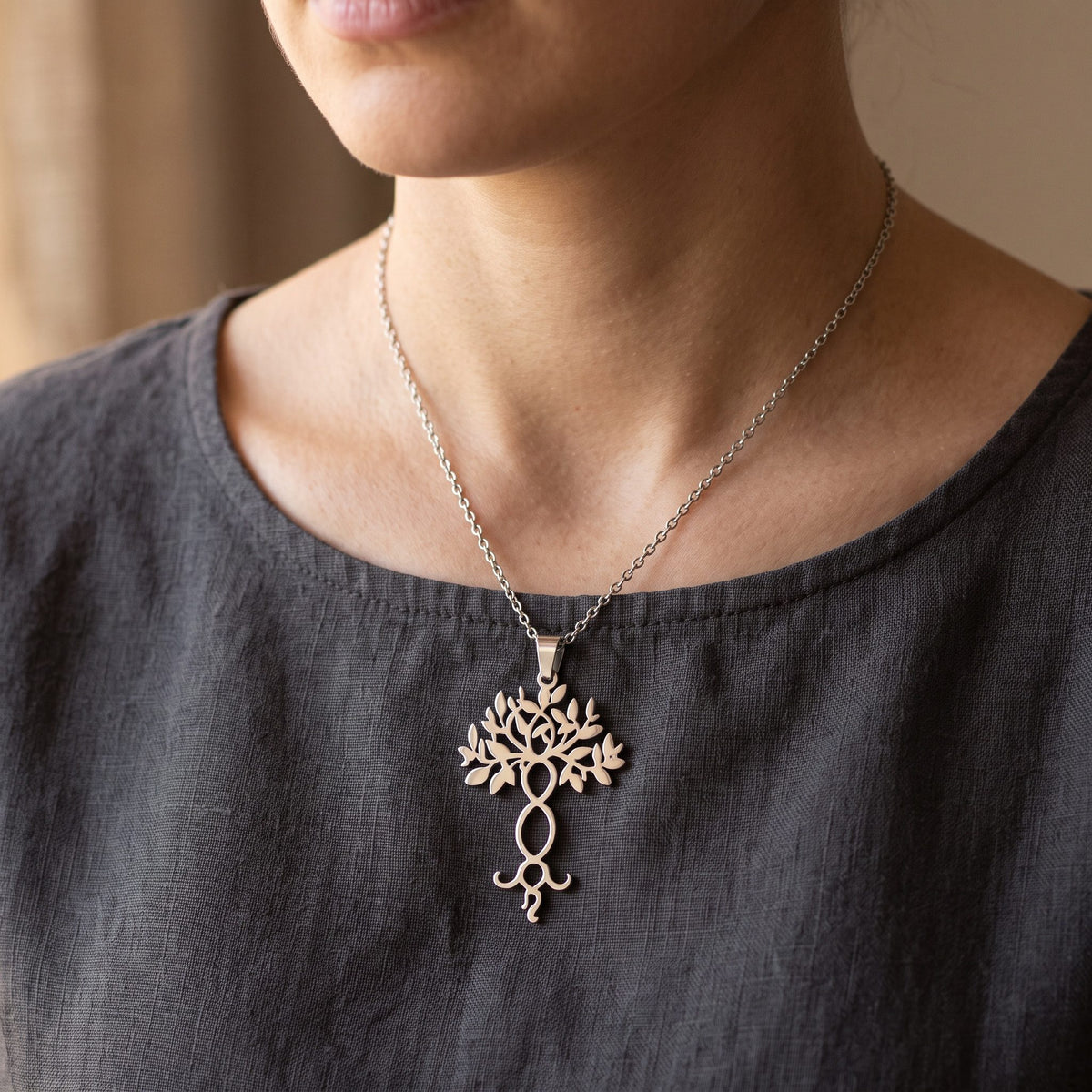 Filigraner Yggdrasil Anhänger an Kette auf dem Brustbein, dunkles Leinenoberteil