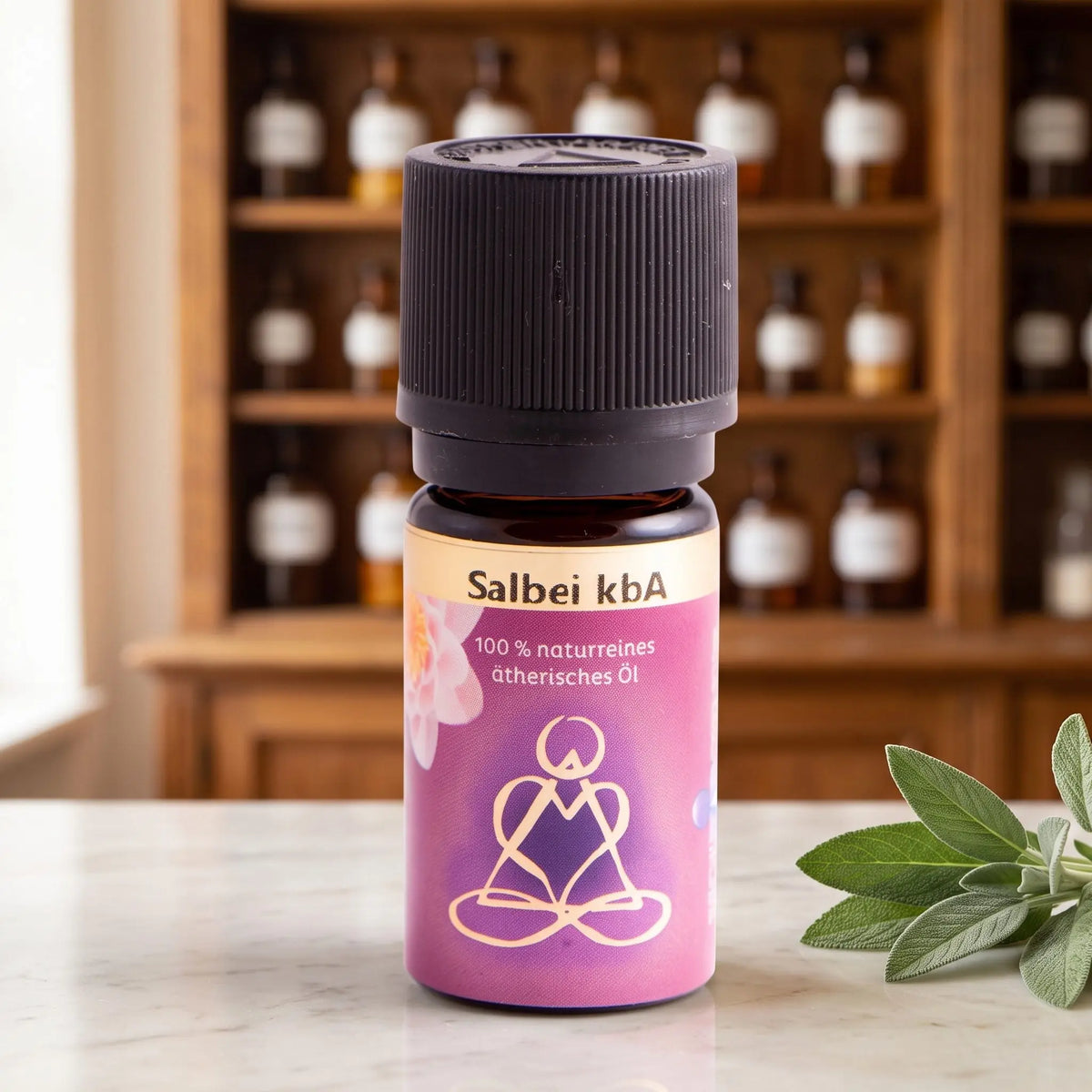 Ätherisches Öl Salbei: Fläschchen aus Braunglas auf Marmortheke vor Apothekerschrank, daneben Salbeiblätter – Spirit of Gaia