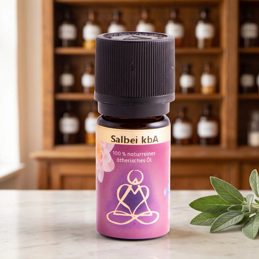 Ätherisches Öl Salbei: Fläschchen aus Braunglas auf Marmortheke vor Apothekerschrank, daneben Salbeiblätter – Spirit of Gaia