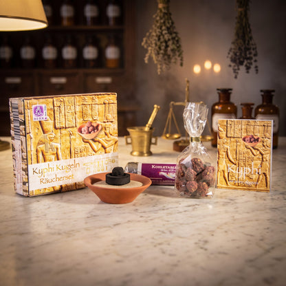 Kyphi Räucher-Set von Berk, Inhalt: handgerollte Kyphi-Kügelchen im Beutel, Tonschale mit Räuchersand, Rolle Räucherkohle und Kyphi-Fibel neben der Schachtel – Spirit of Gaia