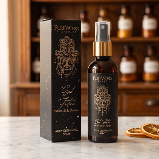 Aura-Spray Good Fortune (Patchouli & Orange) von Pure Works: Sprühflasche mit Goldkragen und schwarze Schachtel auf Marmortheke vor Apothekerschrank – Spirit of Gaia