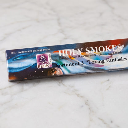 Nahaufnahme der Packung Loving Fantasies Sortiment 3 mit Holy-Smokes-Schriftzug, Berk-Esoterik-Logo und dem Aufdruck 9 x 2 Räucherstäbchen auf Marmor