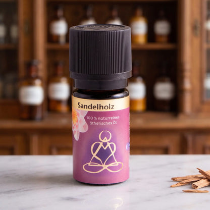 Ätherisches Öl Sandelholz: Fläschchen aus Braunglas auf Marmortheke vor Apothekerschrank, daneben Sandelholzspäne – Spirit of Gaia