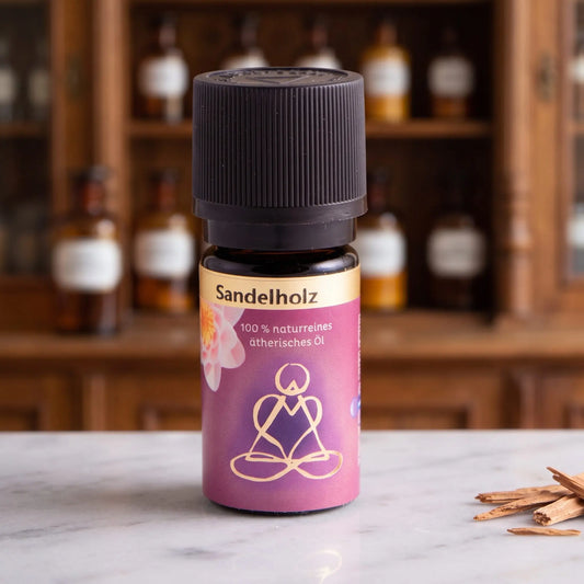 Ätherisches Öl Sandelholz: Fläschchen aus Braunglas auf Marmortheke vor Apothekerschrank, daneben Sandelholzspäne – Spirit of Gaia
