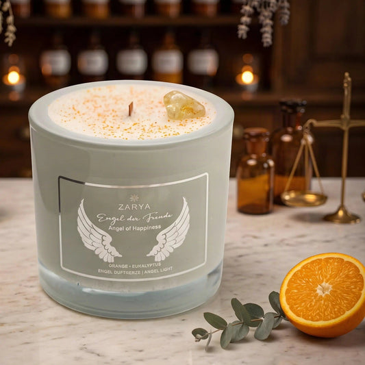 Engelkerze Engel der Freude von Zarya: salbeigrünes Glas mit weißem Aufdruck auf der Marmortheke einer alten Apotheke am Abend, auf dem Wachs ein Citrin, daneben eine halbe Orange und ein Eukalyptuszweig – Spirit of Gaia