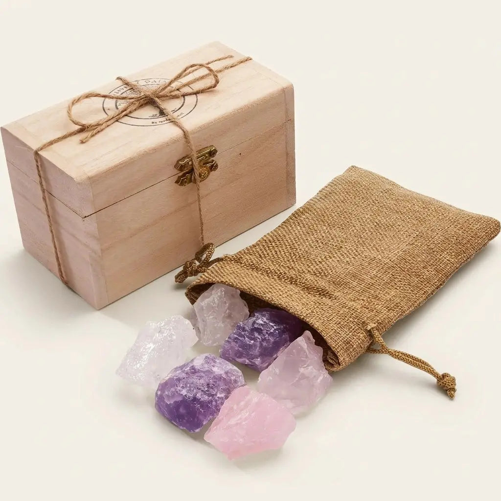 Wassersteine Grundmischung – Holzkästchen mit Jutesäckchen und Rohsteinen Amethyst, Rosenquarz und Bergkristall vor hellem Hintergrund – Spirit of Gaia