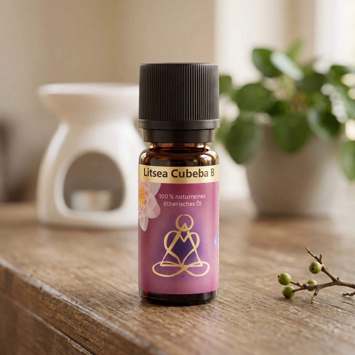 Ätherisches Öl Litsea Cubeba: Fläschchen auf einem Holz-Sideboard im Wohnzimmer, im Hintergrund eine weiße Duftlampe, daneben ein Litsea-Zweig mit Beeren